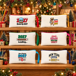 Six cream Christmas pencil cases with red, yellow, green, pink, turquoise and navy zippers and matching hand straps on the shelves of a stationery shop decorated for Christmas