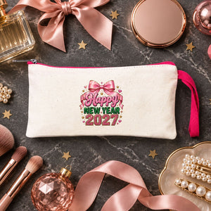 Cream zipper pouch with a pink zipper and a pink bow Happy New Year 2027 print used as a makeup bag on marble with brushes, lipstick and pearl clips