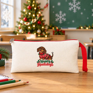 Cream pencil case with a red zipper and a Happy Howlidays dachshund print standing on a school desk in a classroom decorated for Christmas, a class gift for students
