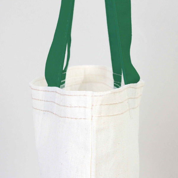 White tote bag with green handles on a light gray background