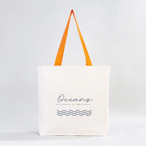 White tote bag with orange handles and 'Oceans' branding on a light gray background