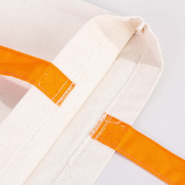 Close-up of a white martial arts gi with orange belt on a light gray background