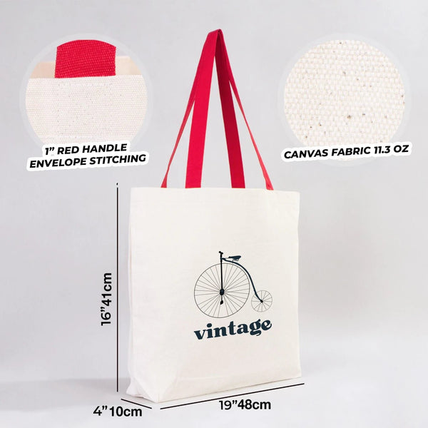 White tote bag with red handles, featuring a bicycle graphic and 'vintage' text, on a light gray background.