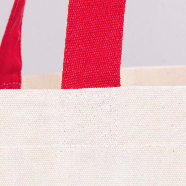 Close-up of a white tote bag with red and beige straps on a light gray background