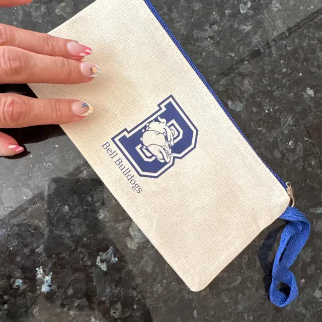 Small pouch with 'Bell Bulldogs' logo held by a hand on a dark surface