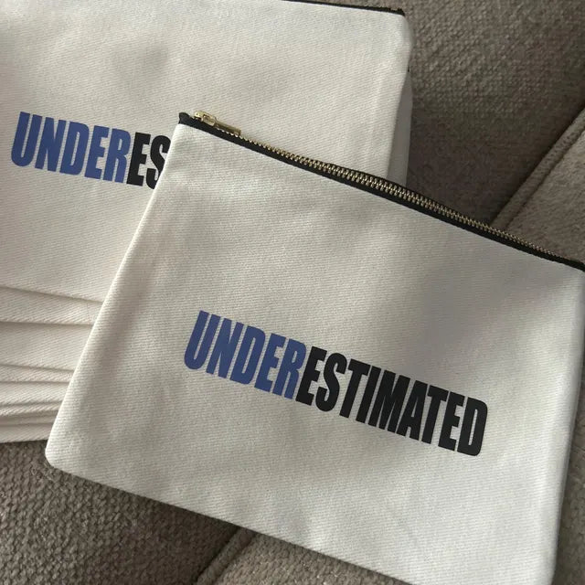 White pouches with 'UNDERESTIMATED' text on a textured surface