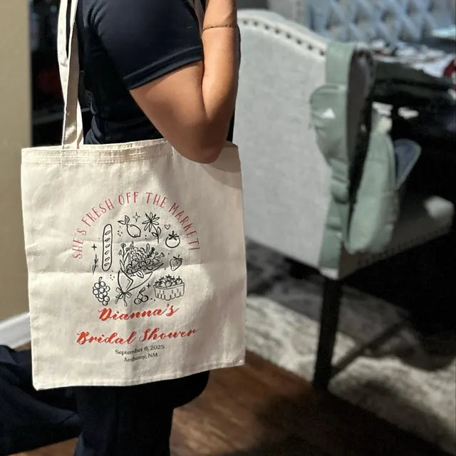 Person holding a tote bag with 'Dianna's Bridal Shower' text and graphics.