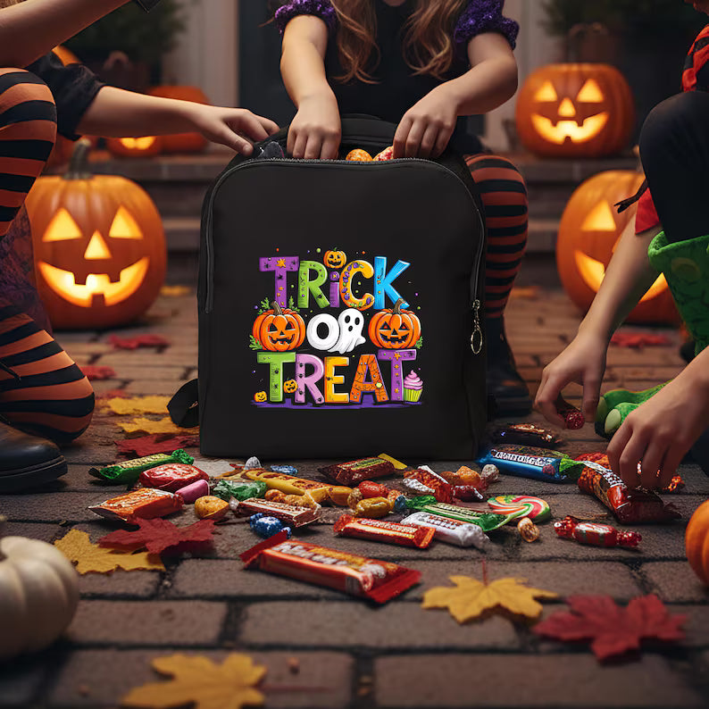 Black backpack with 'Gilmore Ghouls' design in a Halloween setting with pumpkins and candles.