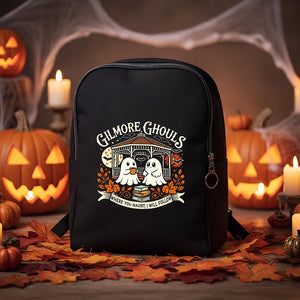 Black backpack with 'Gilmore Ghouls' design in a Halloween setting with pumpkins and candles.