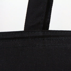 Close-up of a black tote bag with a strap on a white background