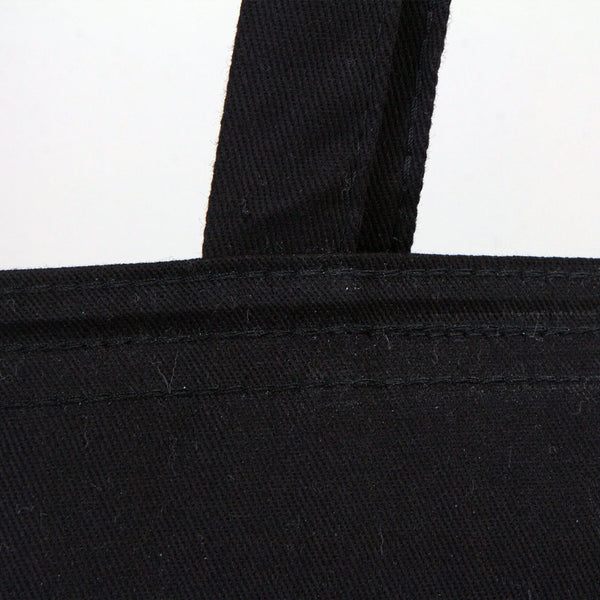 Close-up of a black tote bag with a strap on a white background
